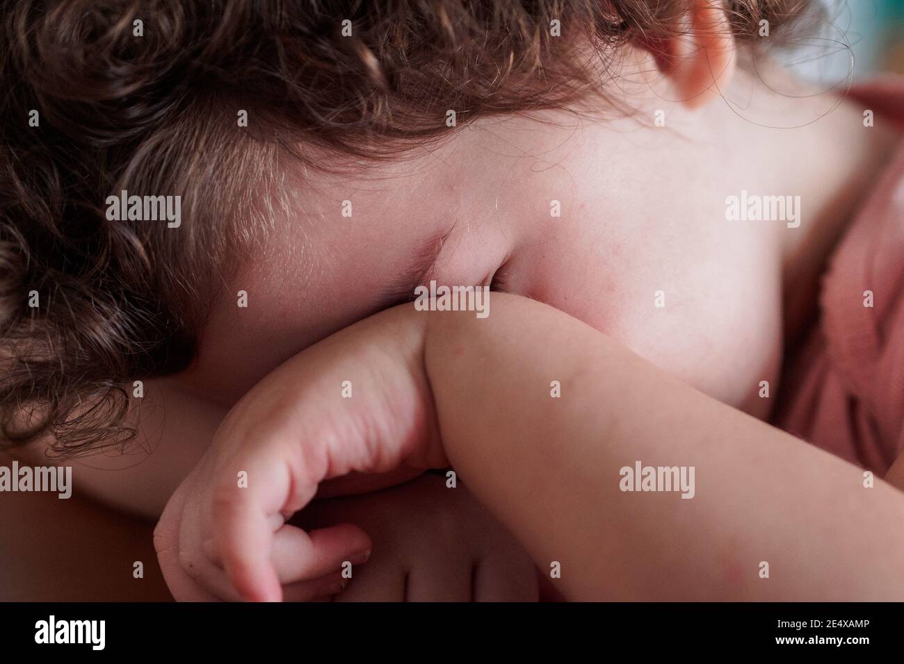 Bashful toddler hides her face behind her hand Stock Photo