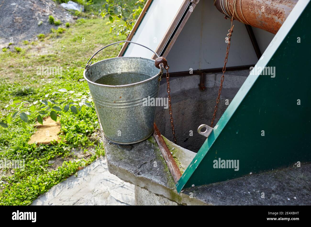 Metal bucket at draw-well in European village. Retro stone water well in  rural area Stock Photo - Alamy