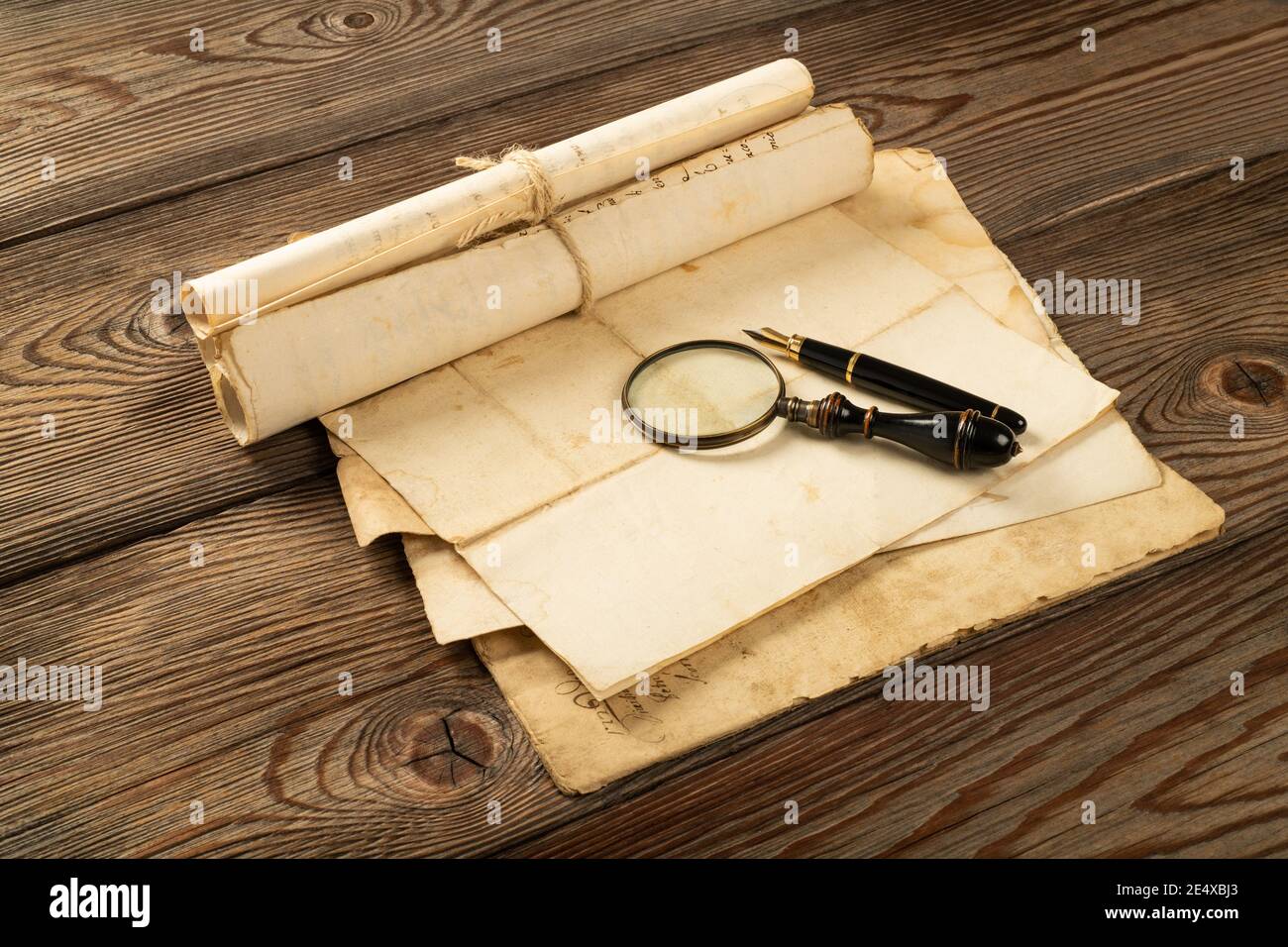 Fountain pen and magnifying glass with old sheets on wood background Stock Photo