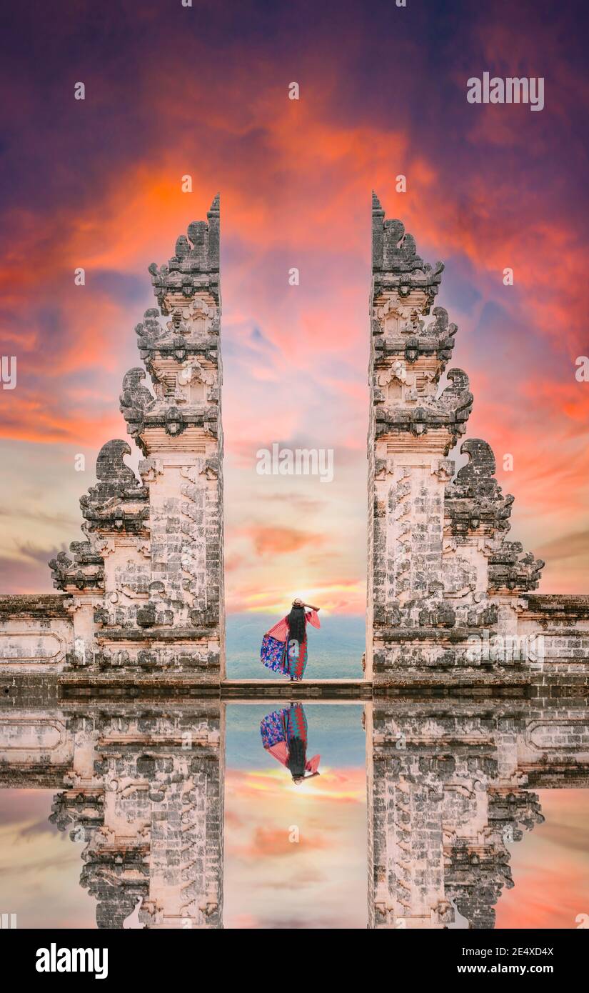 A girl is posing in front of the Gate of Heaven with its reflection in