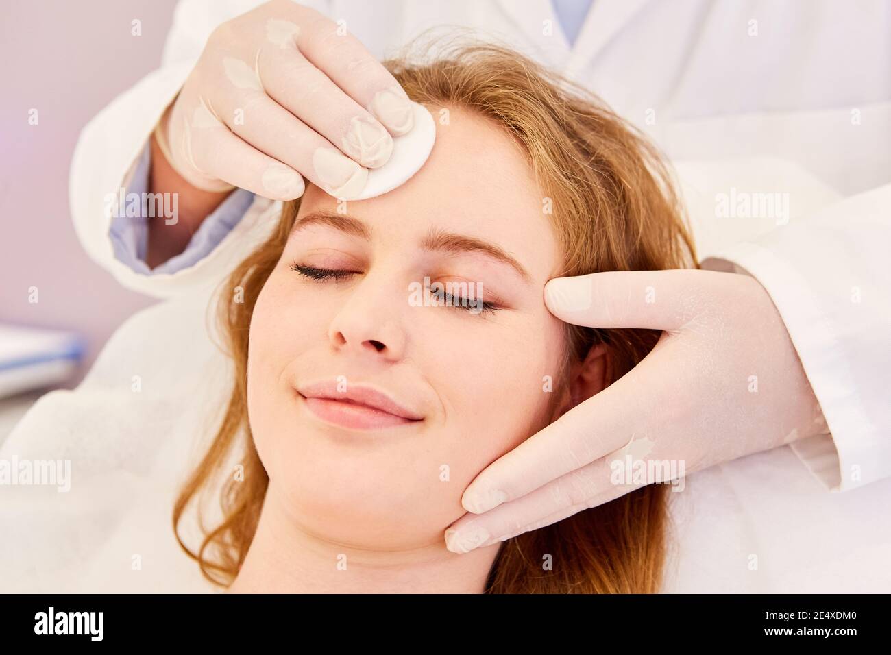 Young woman having professional skin cleansing with cotton pads on her
