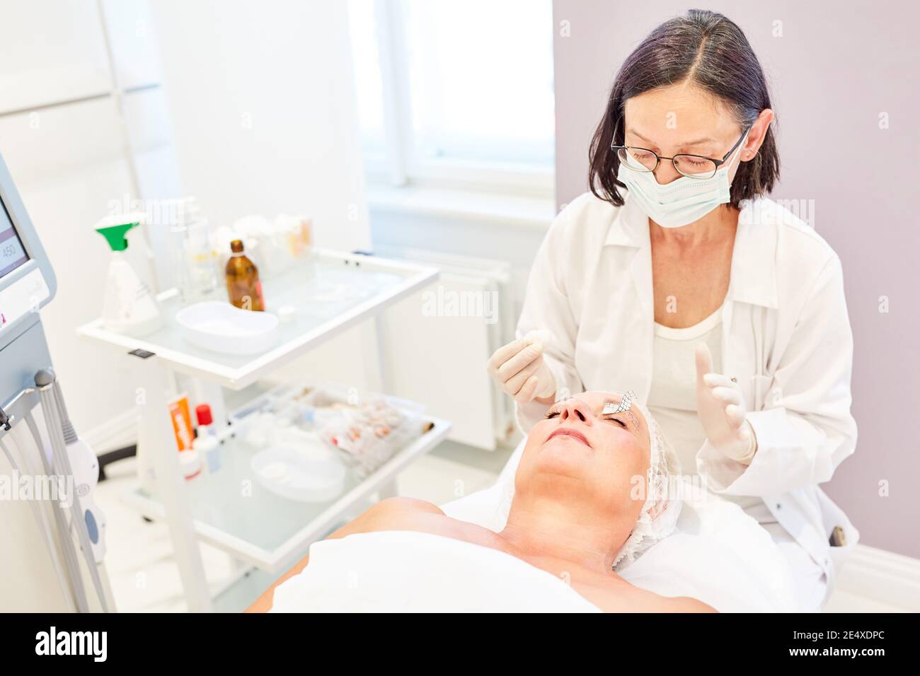 Dermatologist and elderly patient doing eyelid correction in the beauty clinic Stock Photo