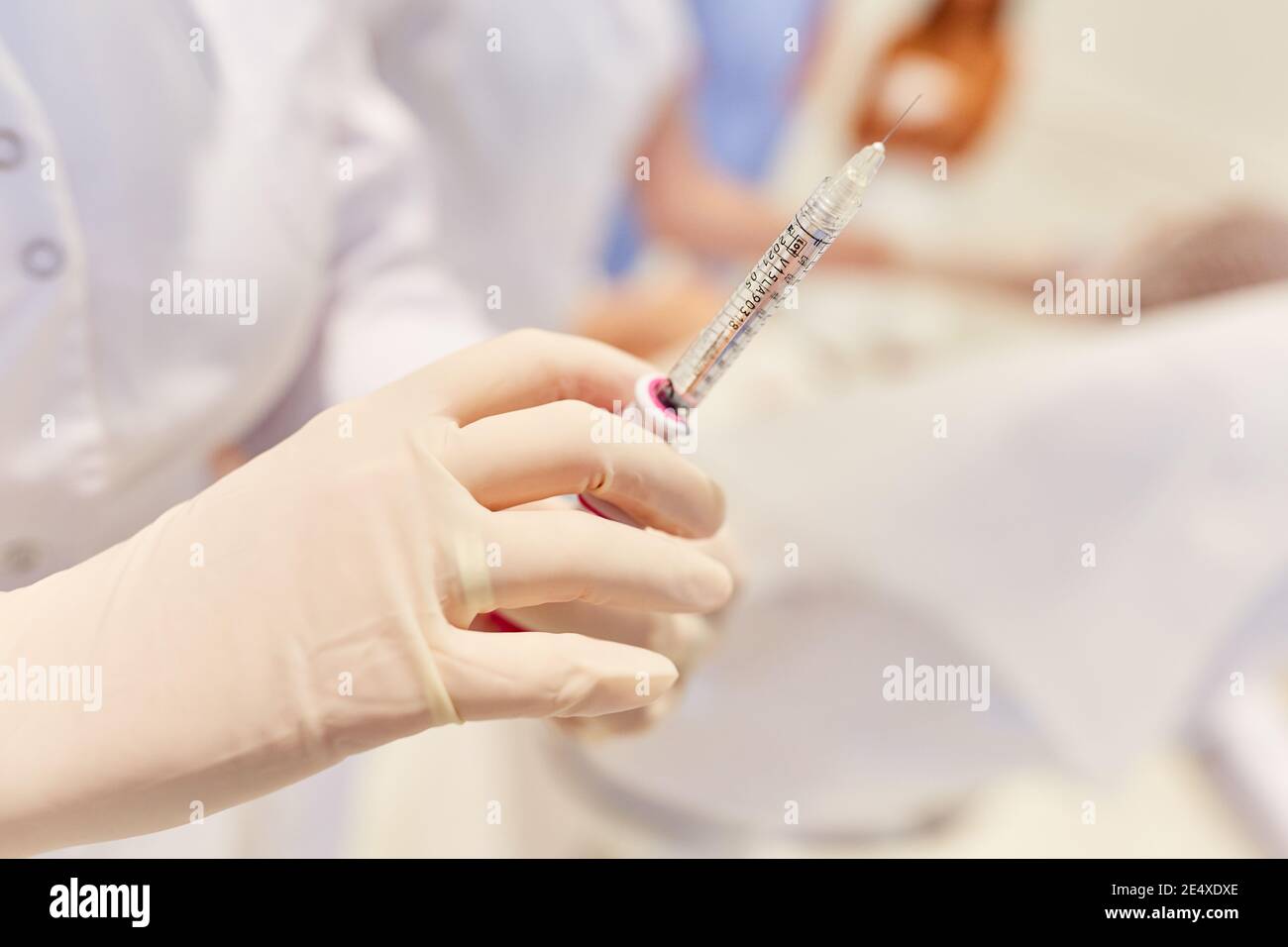 Hand in disposable glove holds syringe with hyaluronic acid for wrinkle injection Stock Photo