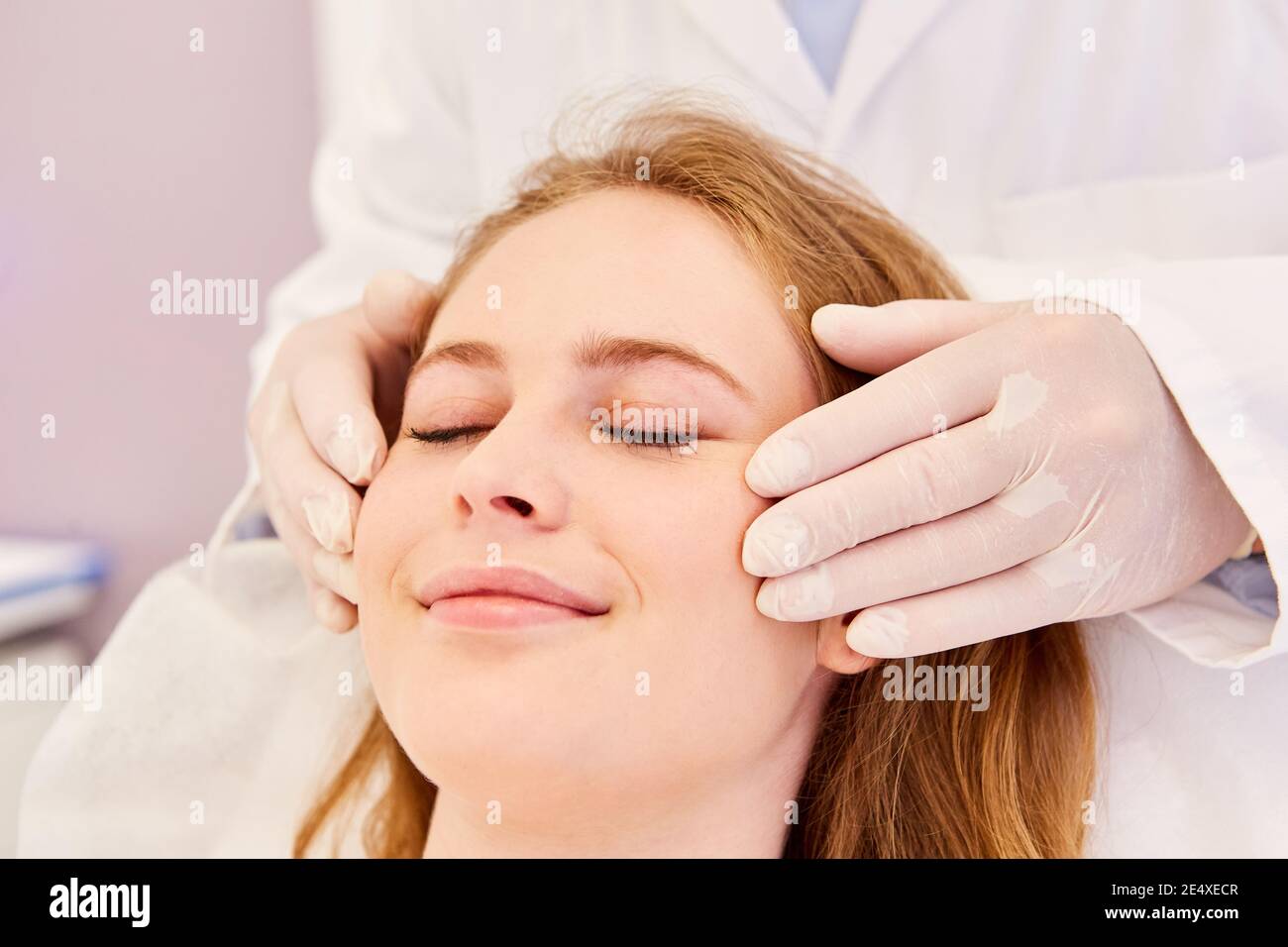 Woman gets wellness facial massage against skin aging in beauty salon Stock Photo