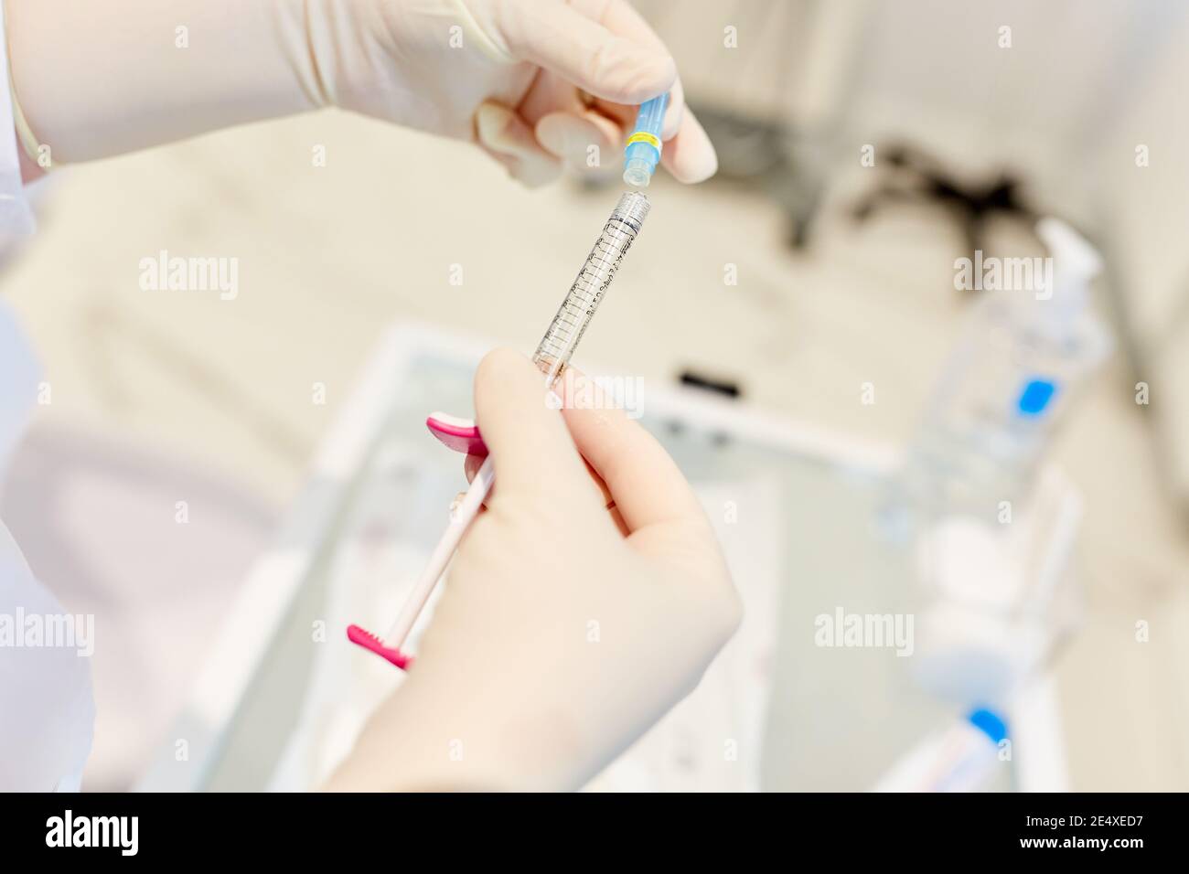 Hands in disposable gloves hold hyaluronic acid syringe for wrinkle injection Stock Photo