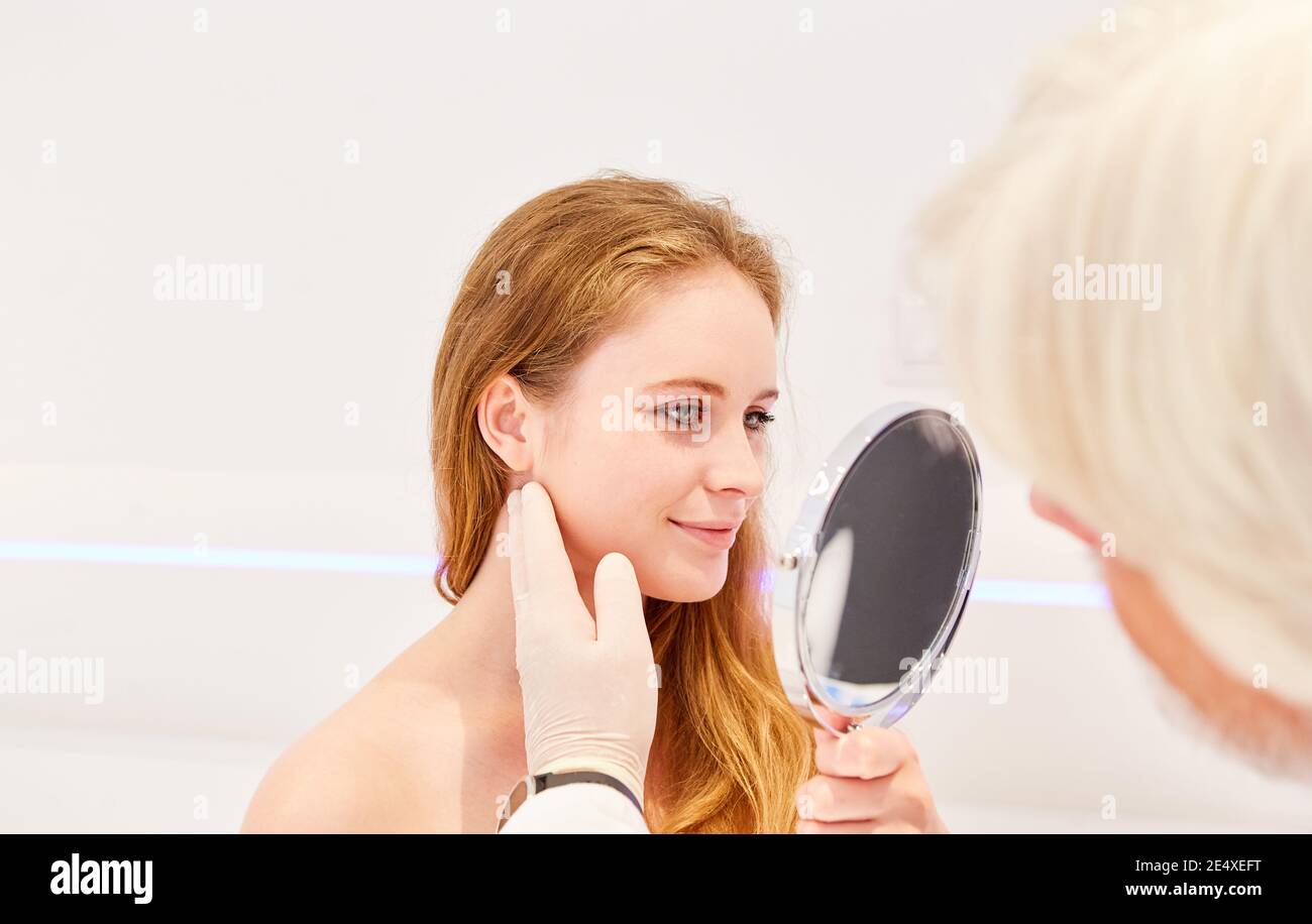 The patient looks in the mirror in the cosmetic studio or in the dermatologist's office Stock Photo