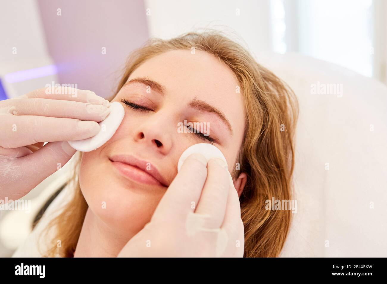 Beautician with cotton pads professionally cleaning the skin of a woman's face Stock Photo