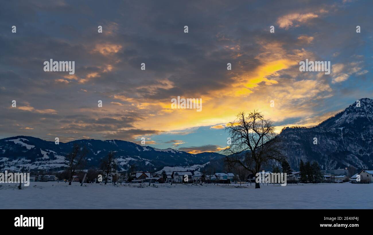 tender colored sunrise in Rhein valley. leuchtender Sonnenaufgang in Dornbirn, Vorarlberg, Austria. red and orange colored dawn in winter, with trees Stock Photo