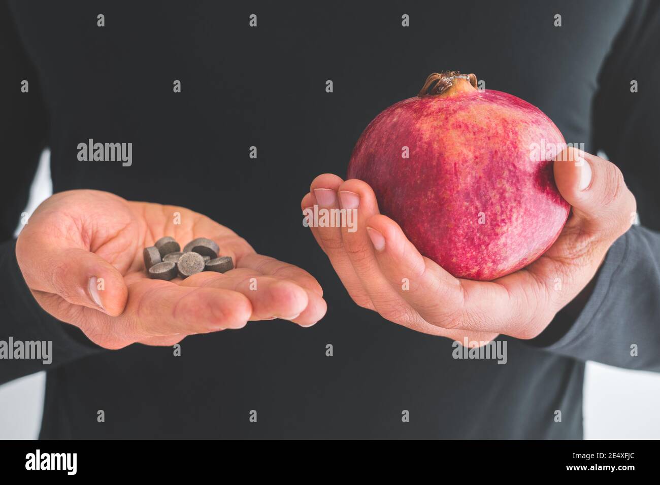 Man hands with iron supplements and pomegranates to treat iron deficiency anemia Stock Photo
