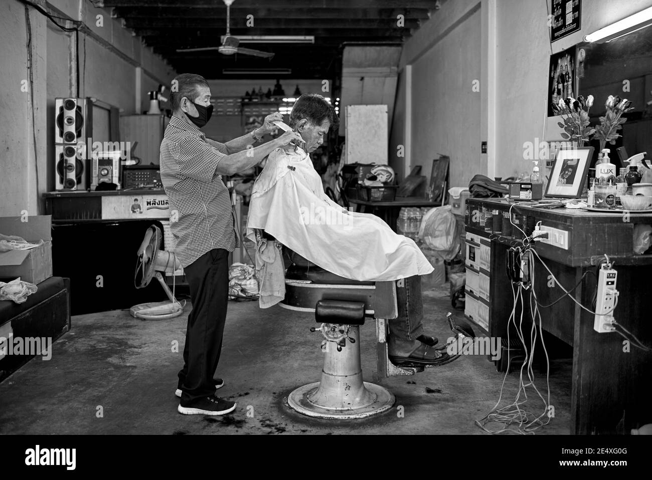 Thailand barber shop with vintage equipment and layout in downtown Bangkok with man receiving haircut. Thailand S. E. Asia.black and white photography Stock Photo