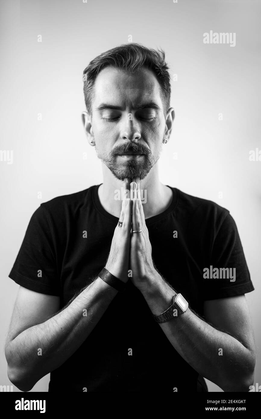 Peaceful calm man with closed eyes and hands together over the chest