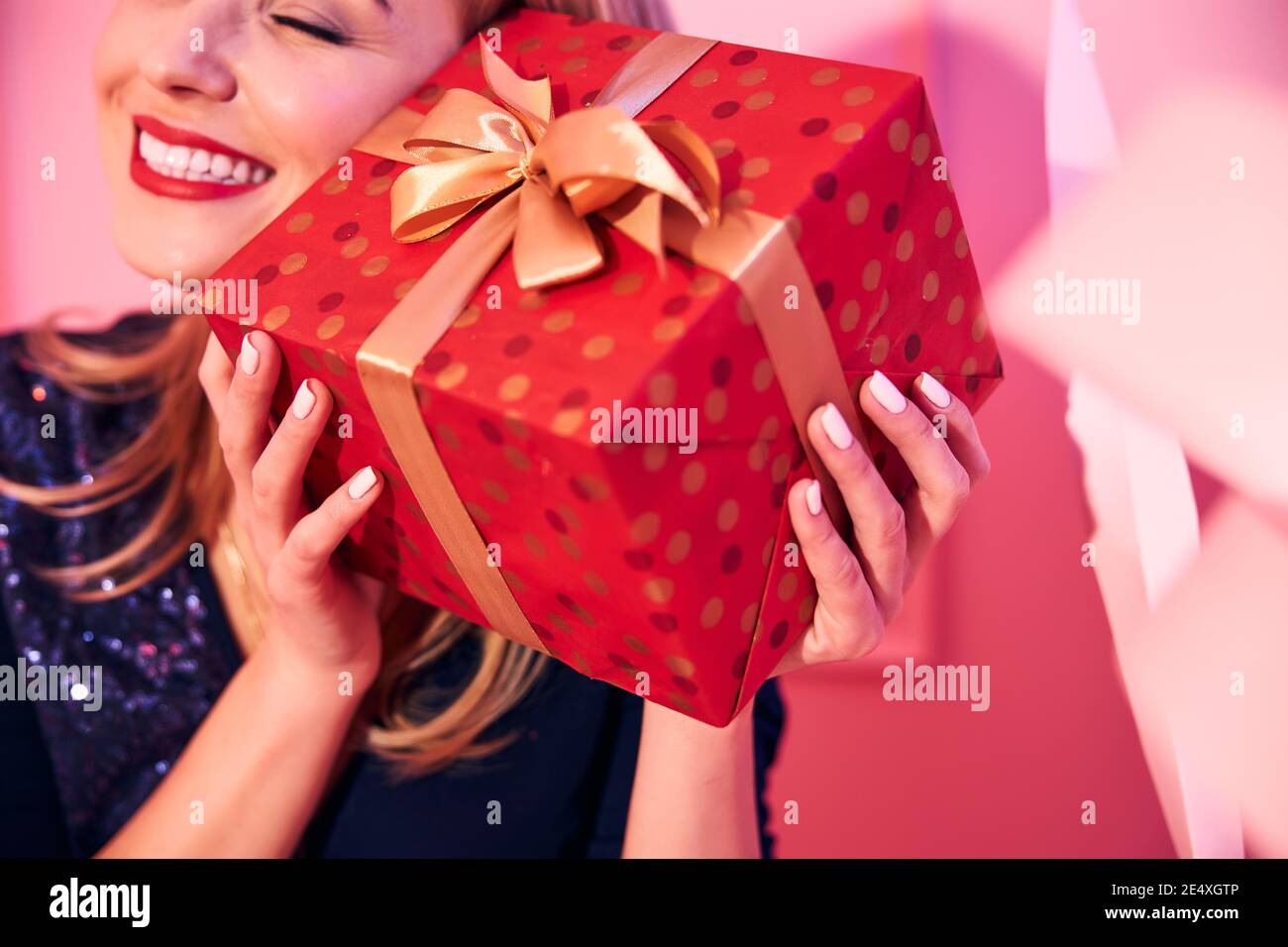 Happy lady pressing the gift box to her ear Stock Photo