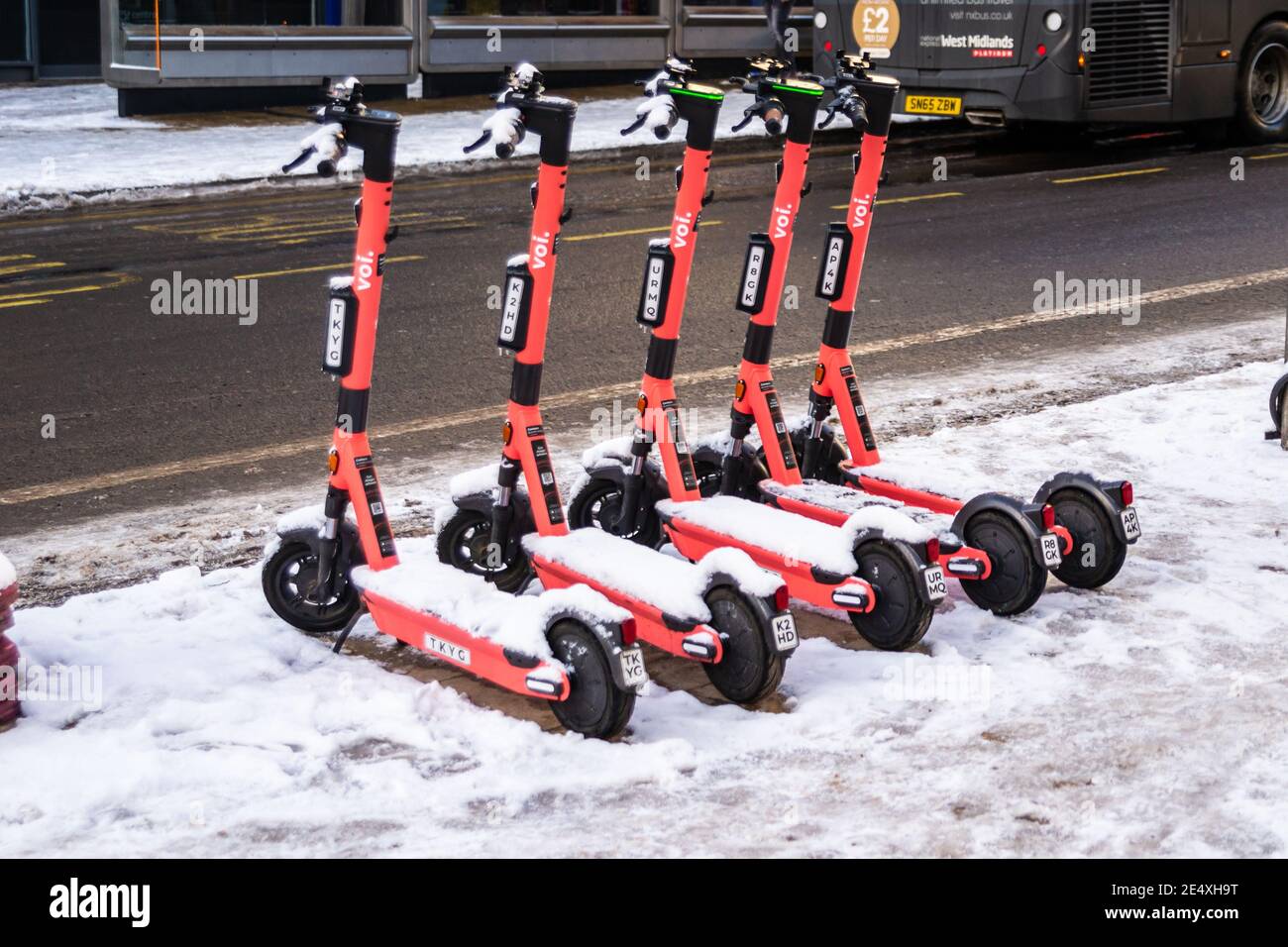 Birmingham, West Midlands, UK. 25th January 2021 - Voi electric scooters lined up in the snow on Bull Street near to The Square Peg pub. Credit: Ryan Underwood / Alamy Live News Stock Photo