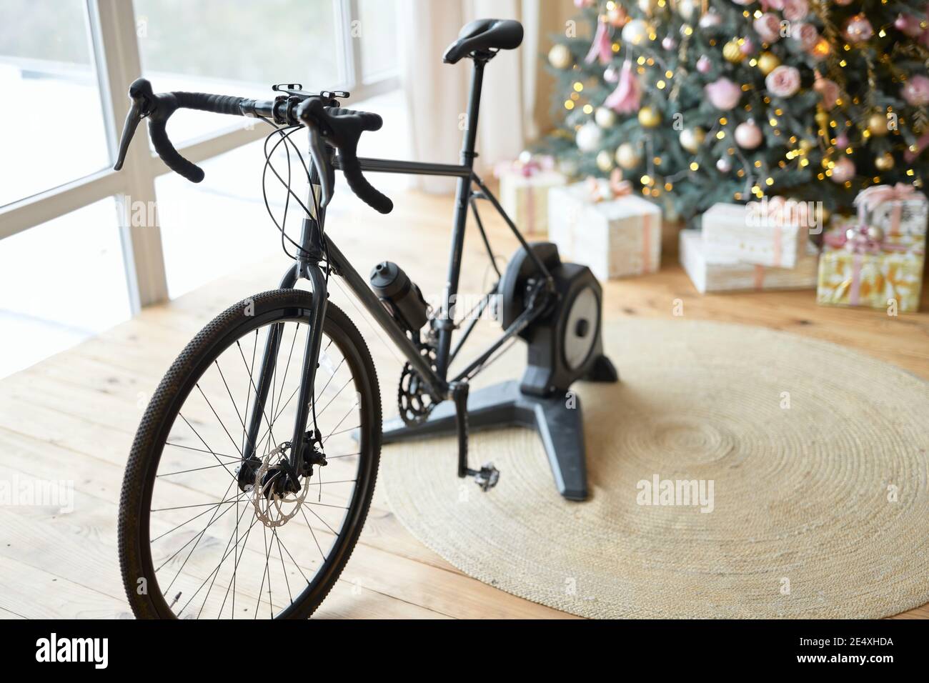 Bicycle trainer or stationery bike in room with wooden floor and Christmas presents under the tree Stock Photo