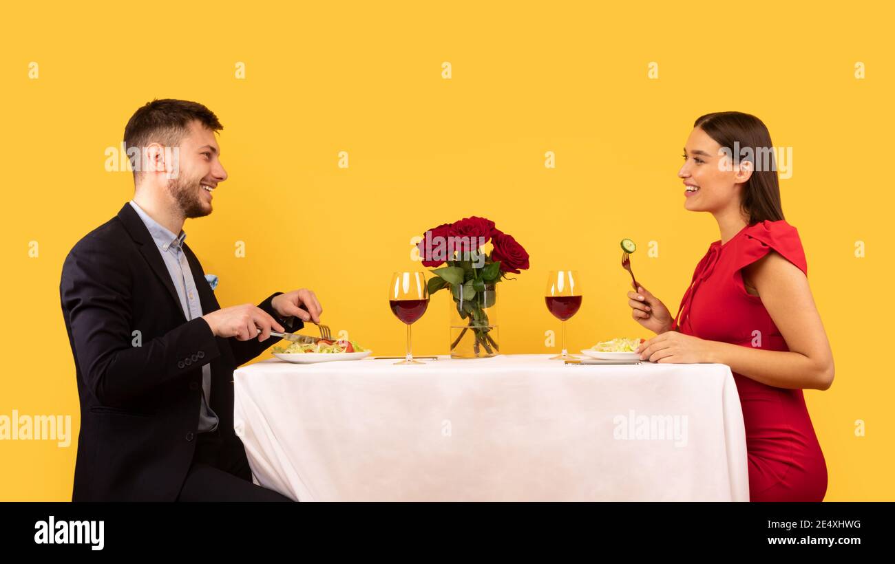Happy Couple Dating Having Romantic Dinner Sitting Over Yellow Background Stock Photo