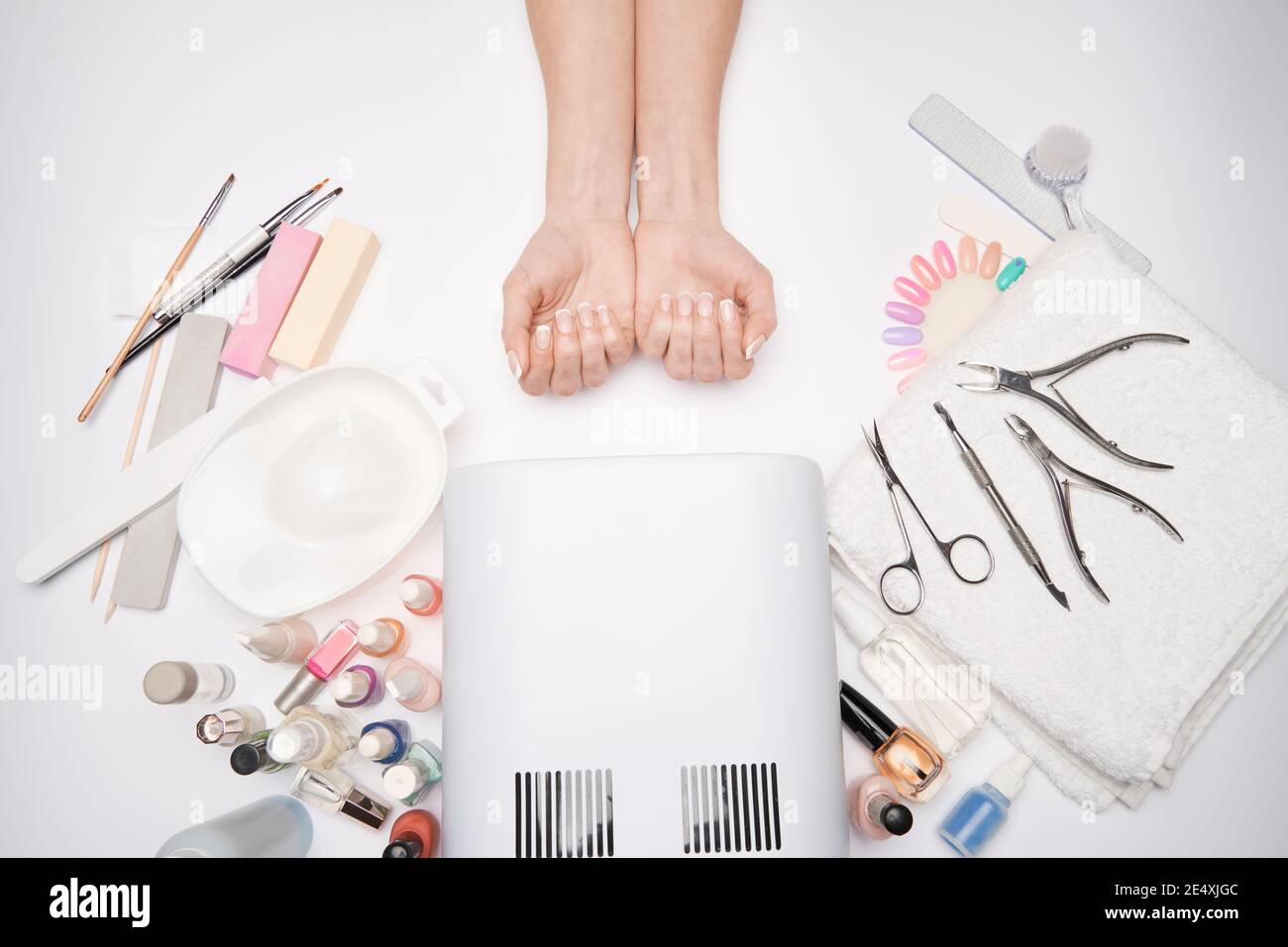 manicure and pedicure items - nail polish drying lamp, nail file, scissors and brushes over light background Stock Photo