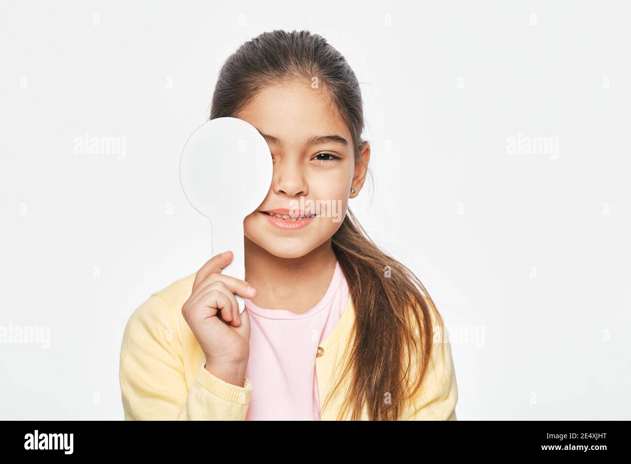 Hispanic little girl having eye exam with one eye covering using a