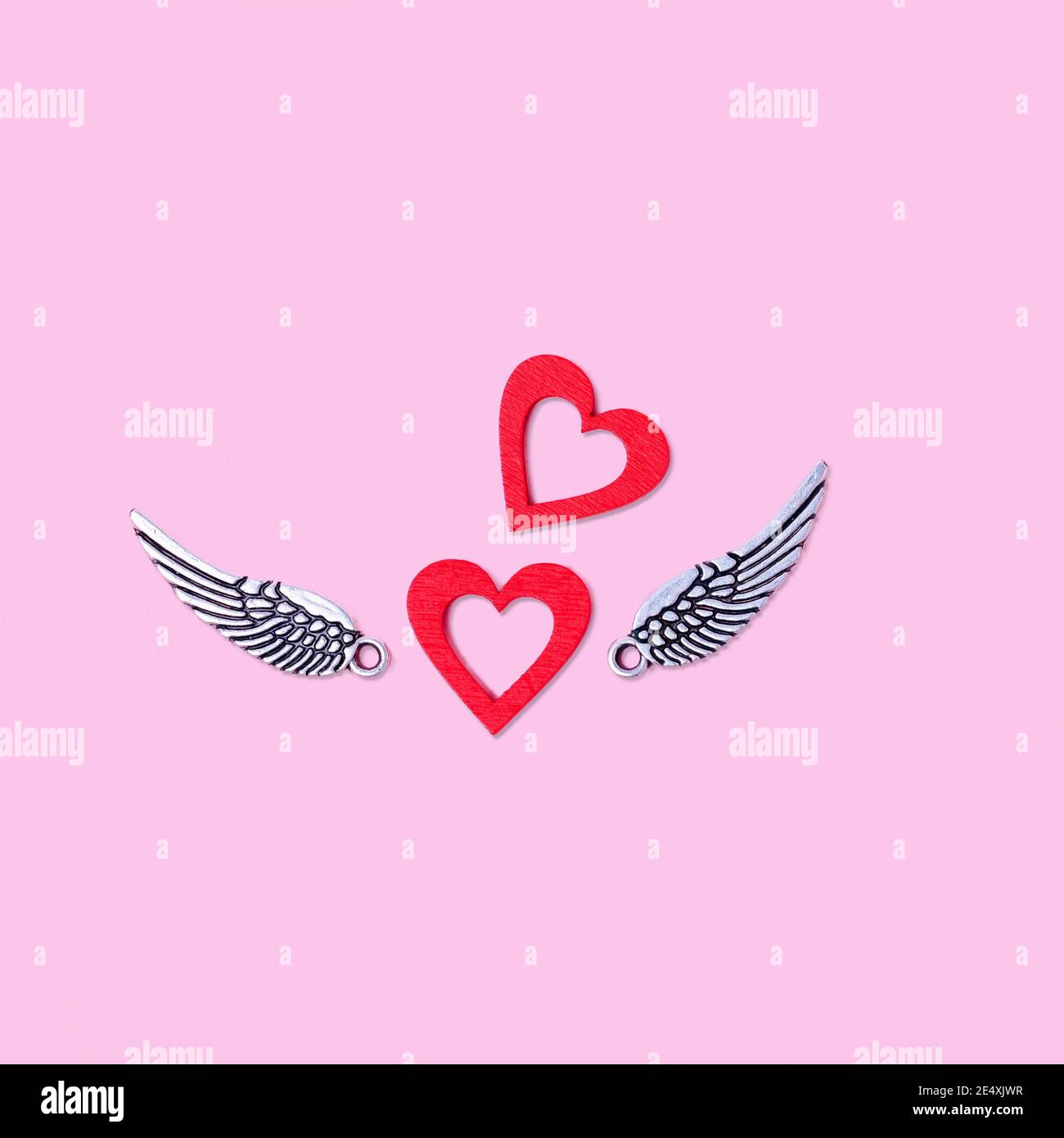 Two red hearts with silver wings on a pink background Stock Photo