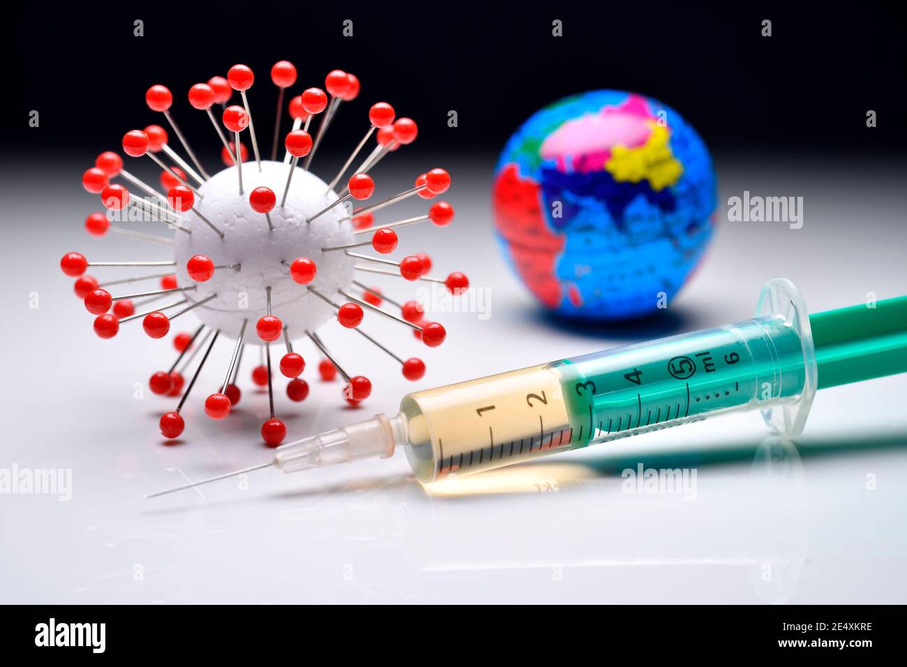 Coronavirus model, globe and vaccination syringe, covid vaccine Stock Photo