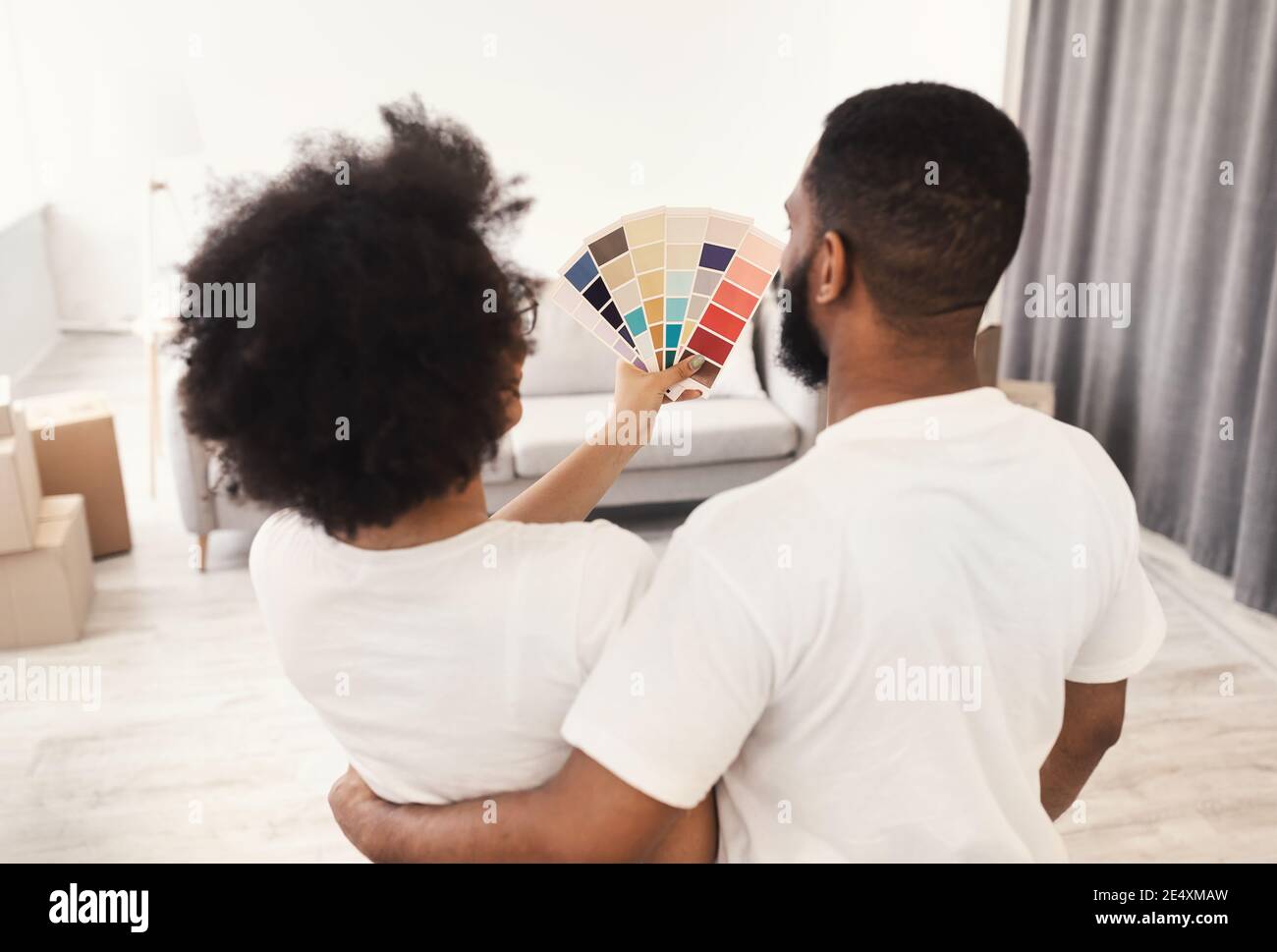 Black Couple Choosing Color For Walls Painting At Home, Rear-View Stock Photo