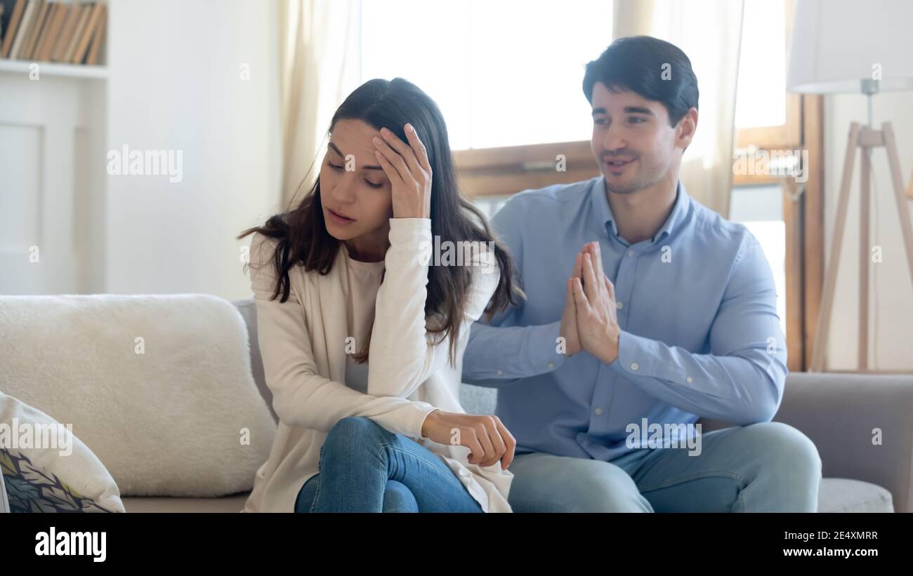 Worried husband asking about his wife's salary while sitting on the couch.
