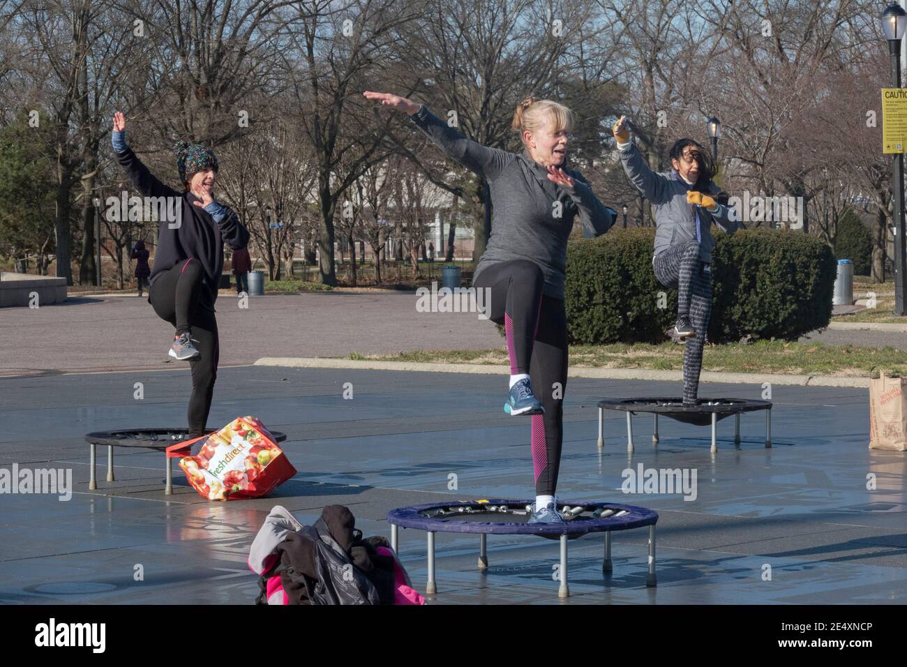 3 women at a rebounding class which combines vigorous movements while jumping on a small trampoline. In flushing Meadows Corona Park in Queens, NYC. Stock Photo