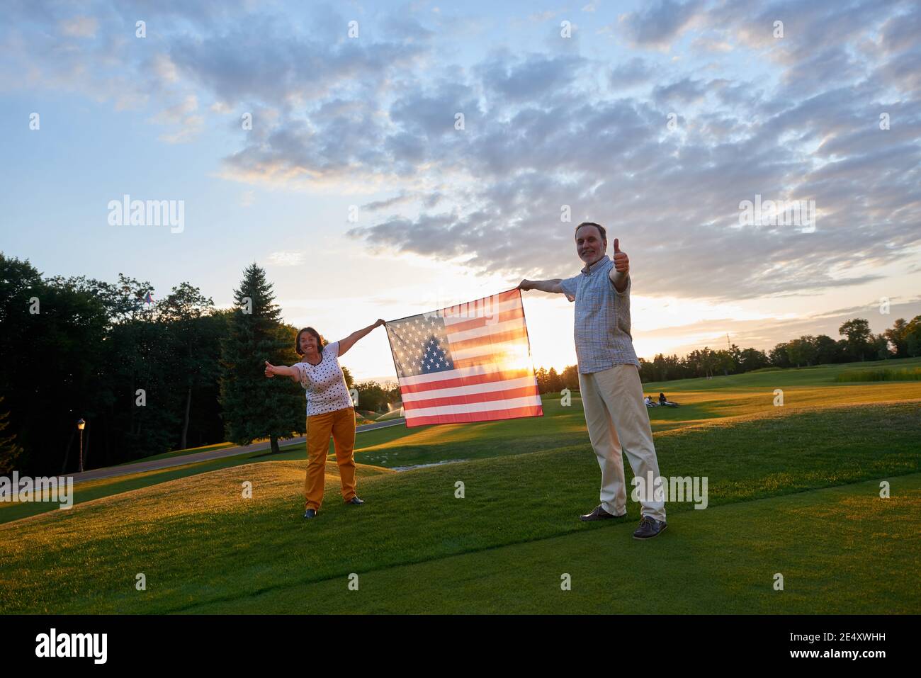 Couple holding us flag and showing thumb up. Stock Photo