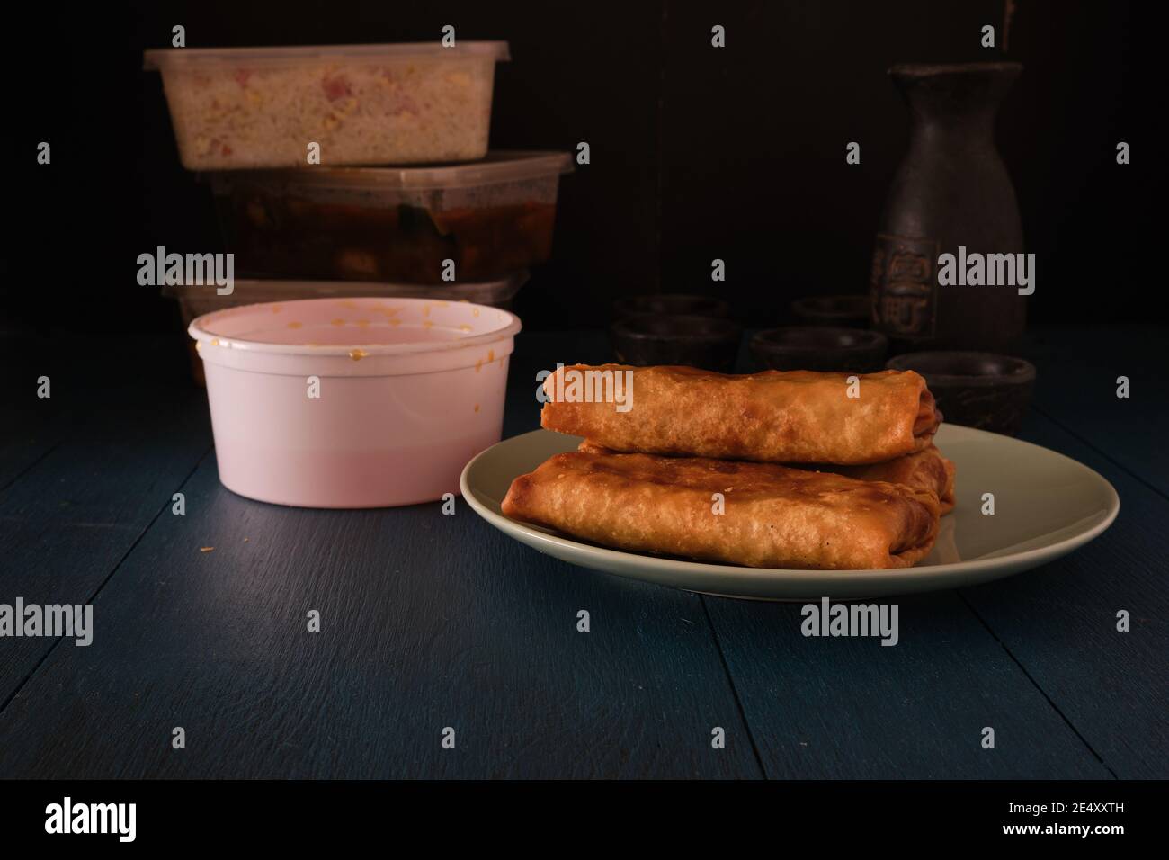 Photo of three spring rolls with sauce over a blue table in a dark enviroment Stock Photo