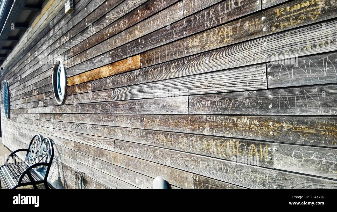 Side view of graffiti scratched into wooden planks on building at the RNLI building at Southend Pier Stock Photo