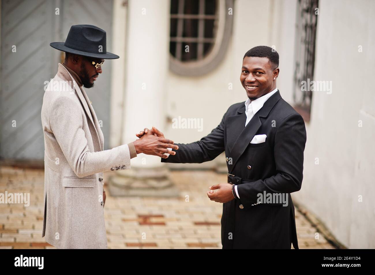 Two fashion black men shake hands each other. Fashionable portrait of