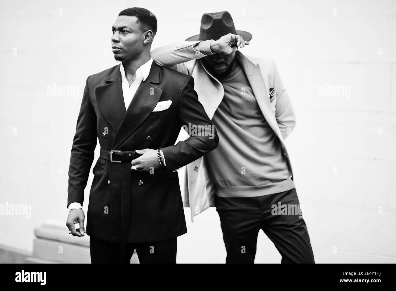 Two fashion black men. Fashionable portrait of african american male models. Wear suit, coat and hat. Stock Photo