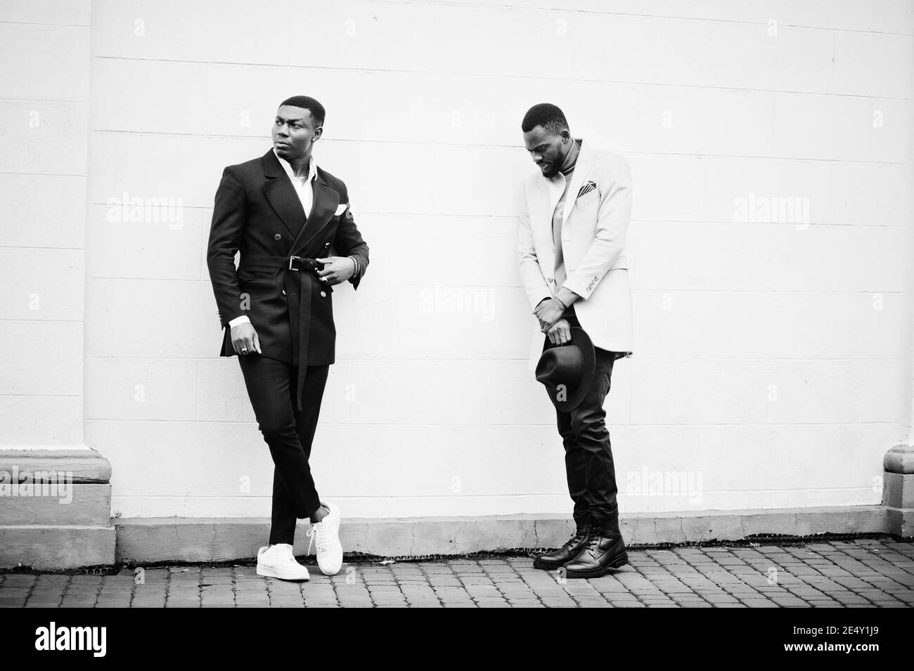 Two fashion black men. Fashionable portrait of african american male models. Wear suit, coat and hat. Stock Photo
