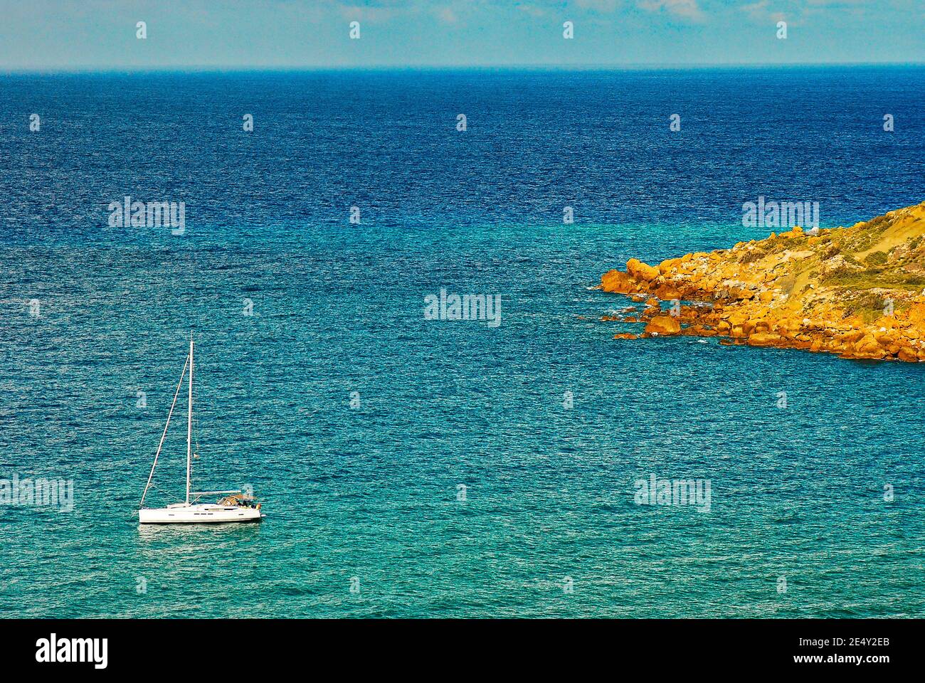 Ramla bay view on Mediterranean sea with the rocky shore and sailing boat around Maltese islands Stock Photo