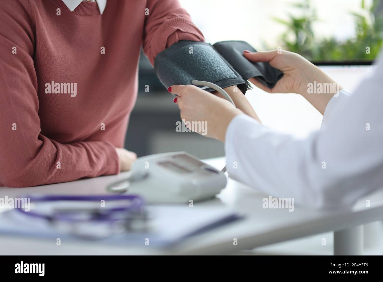 Doctor measures patient's blood pressure at appointment Stock Photo