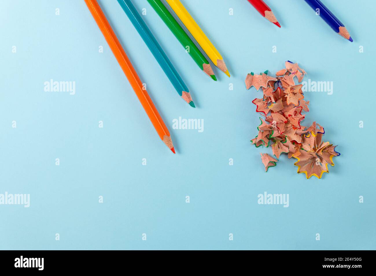 Sharpened colored pencils and pencil shavings on pastel blue color. Rainbow or LGBT pencils. Top view Stock Photo