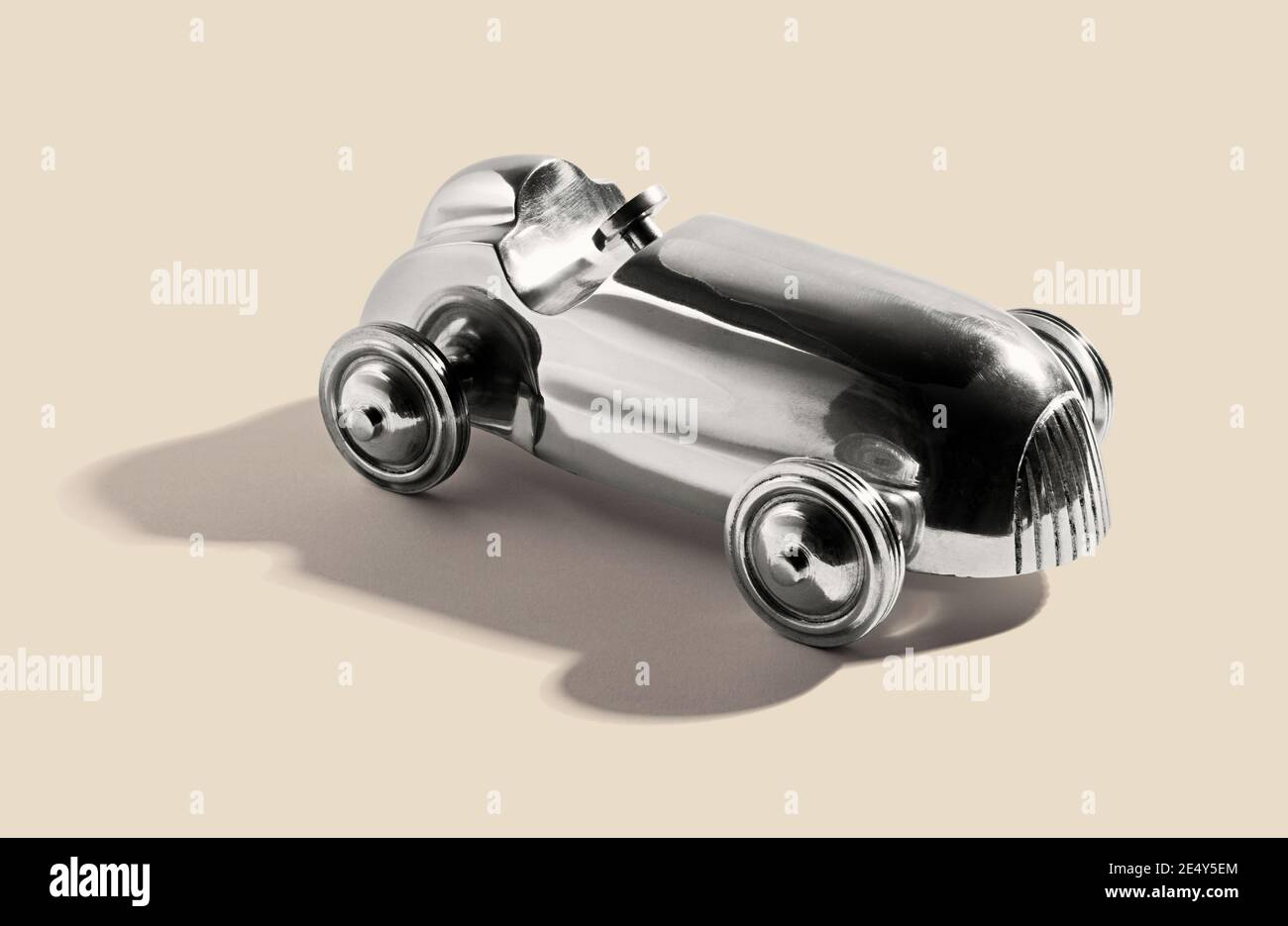 Chromed silver vintage two sealer open sports car toy with integral wheels, on a white beige with shadow Stock Photo