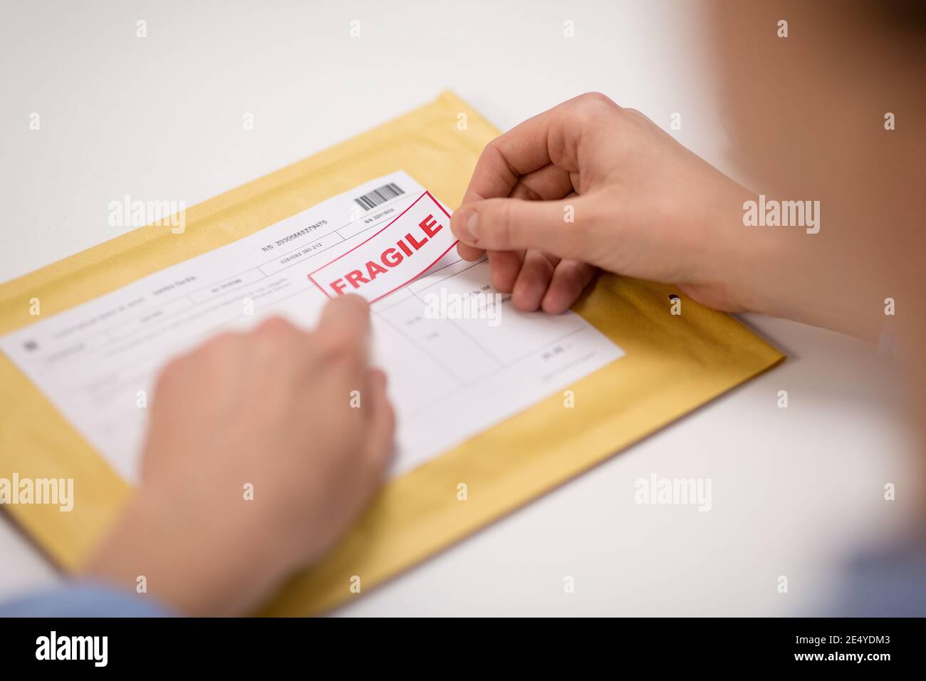 hands sticking fragile marks to parcel in envelope Stock Photo