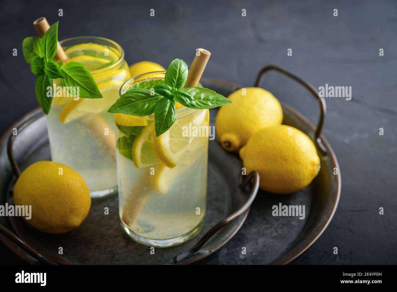 Lemonade with lemon and basil, cold refreshing drink in glasses on