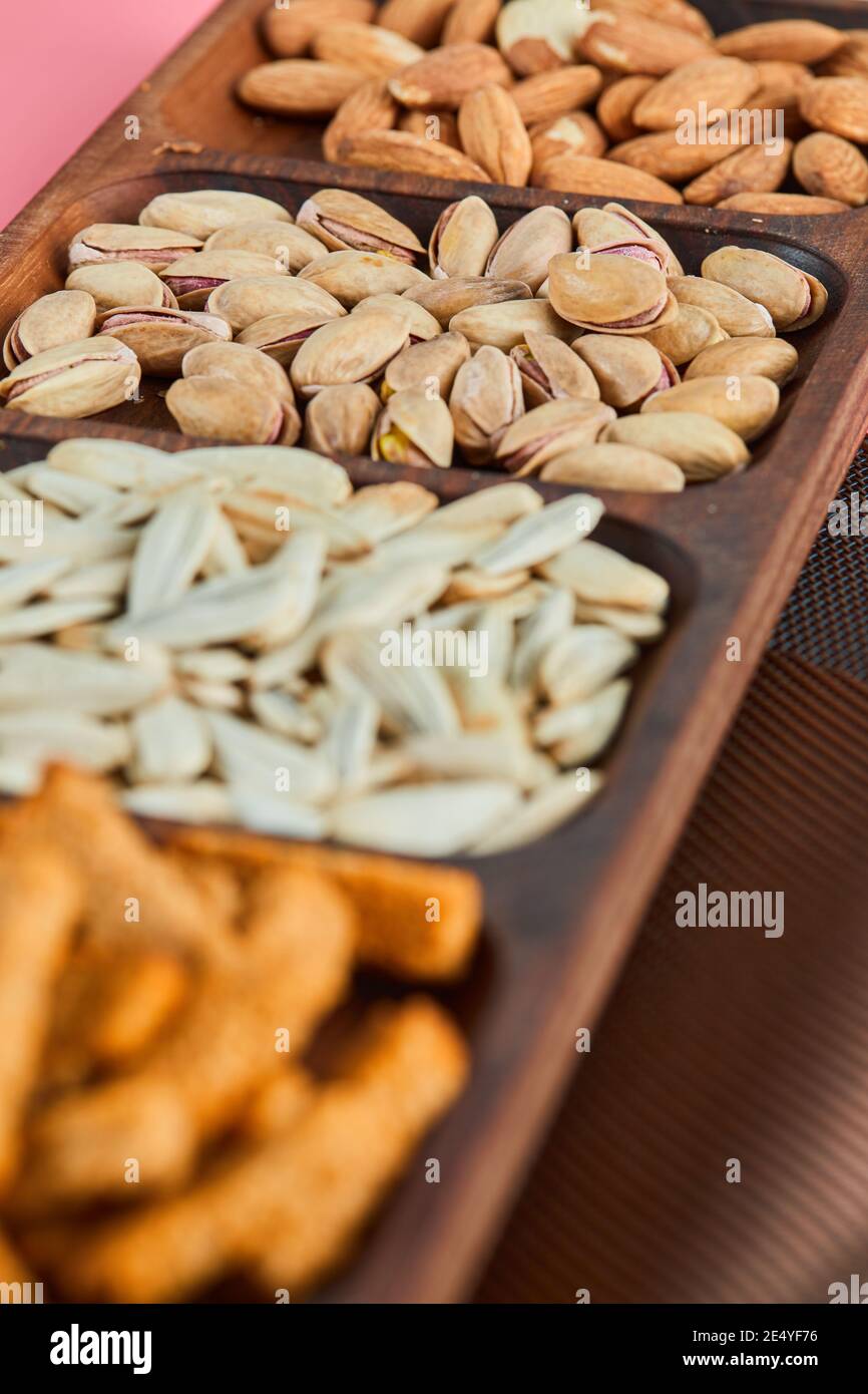 Pistachios, almonds, crackers, and sunflower seeds on wooden plate