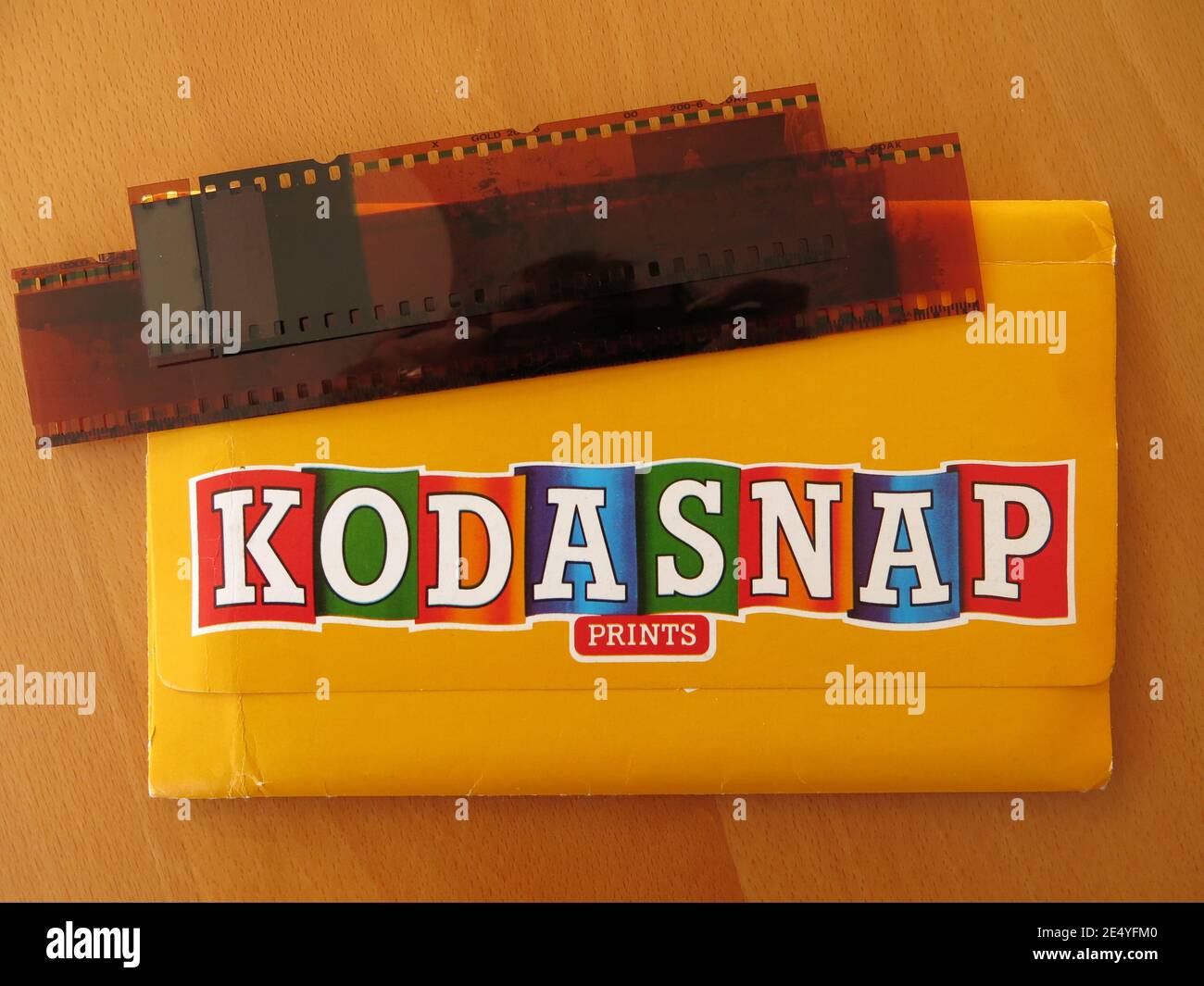 A strip of negatives and yellow photo wallet from Kodasnap, one of the photographic printing companies which offered mail-order film developing. Stock Photo