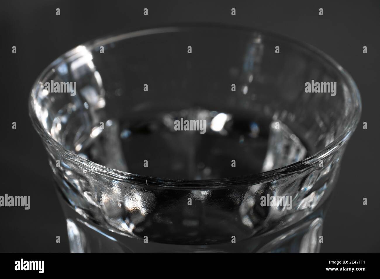 Top of a drinking glass filled with fresh water against a dark