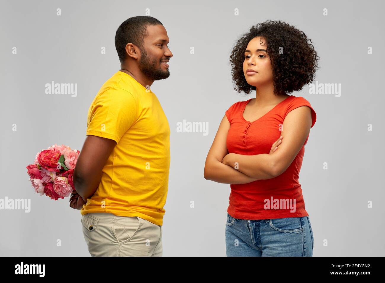 man hiding bunch of flowers behind back from woman Stock Photo