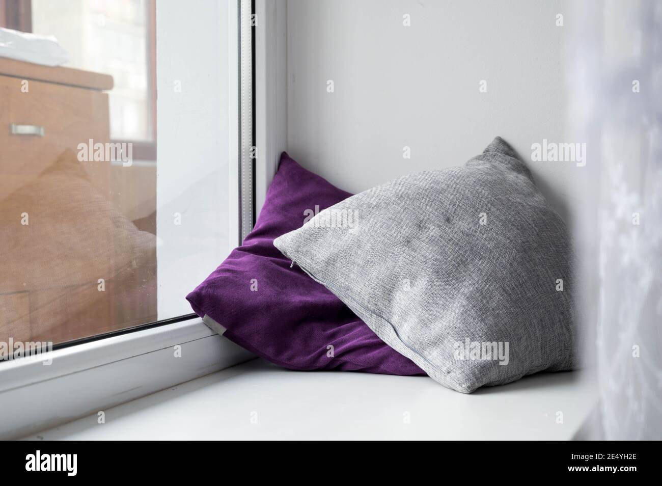 Soft cushions on white sill. Cozy pillows. Stock Photo