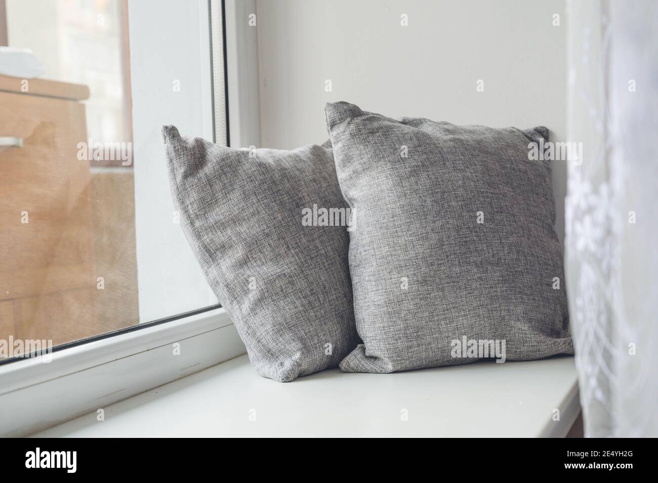 Soft cushions on white sill. Cozy pillows. Stock Photo