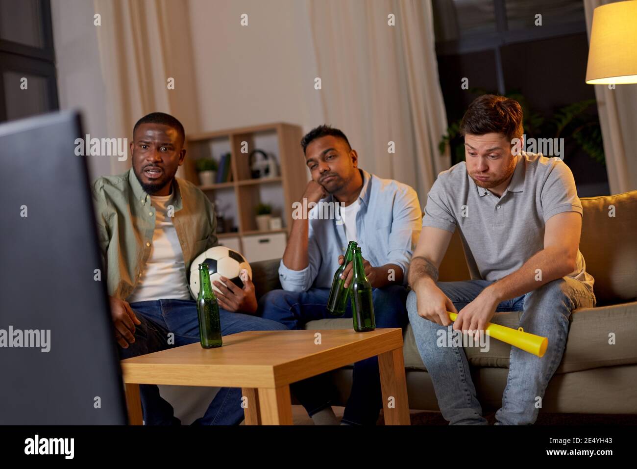 sad friends with beer watching soccer at home Stock Photo