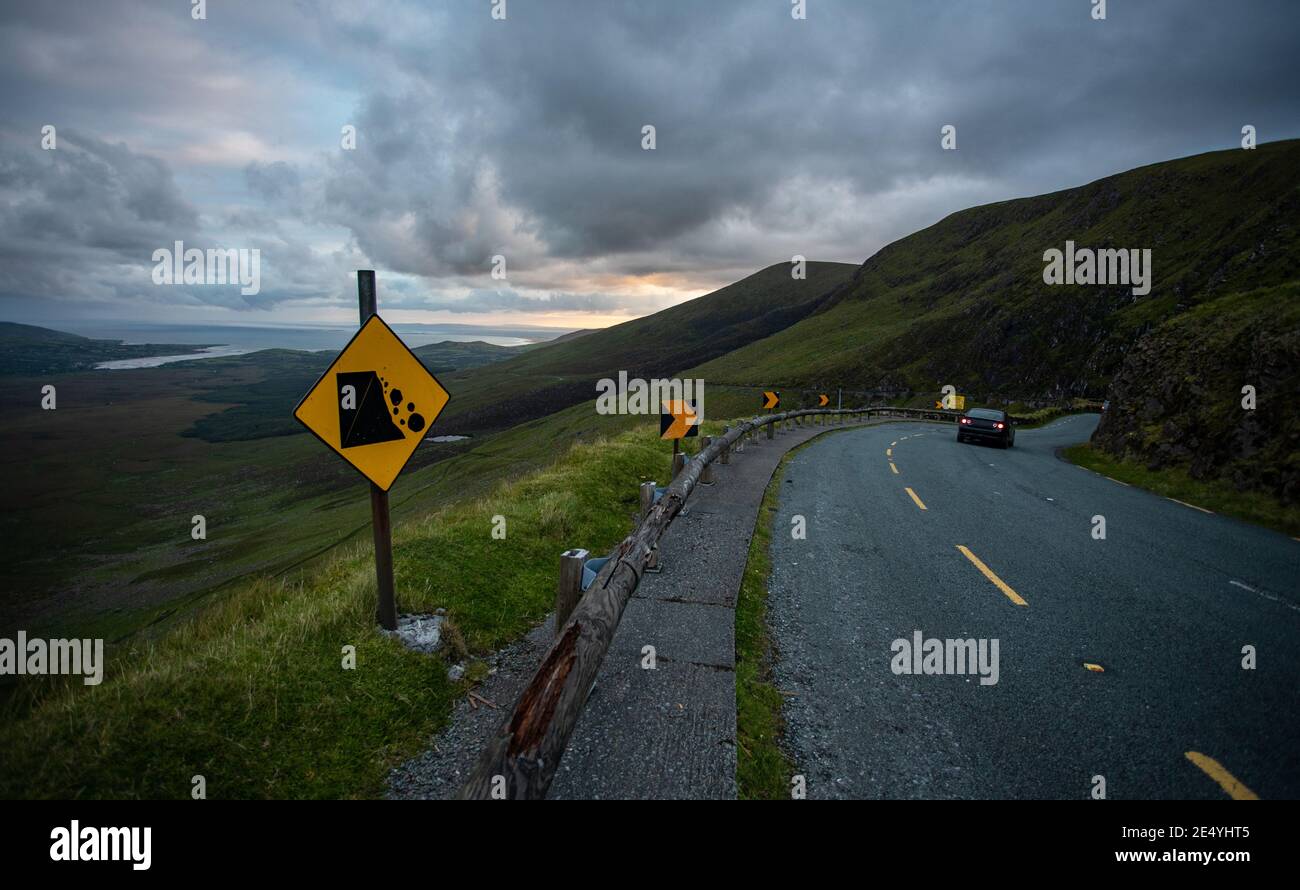 Car driving through the  top of the Connor pass road on the Dingle peninsula, County Kerry, Ireland, Narrow winding road and falling rocks sign Stock Photo
