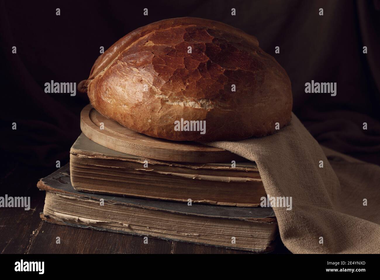 loaf of bread, in futuristic style , on old books, wooden table, brown background, no people, horizontal Stock Photo