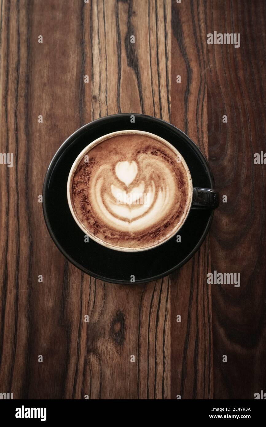 A cup of coffee with latte art on top on wooden table, top view Stock ...