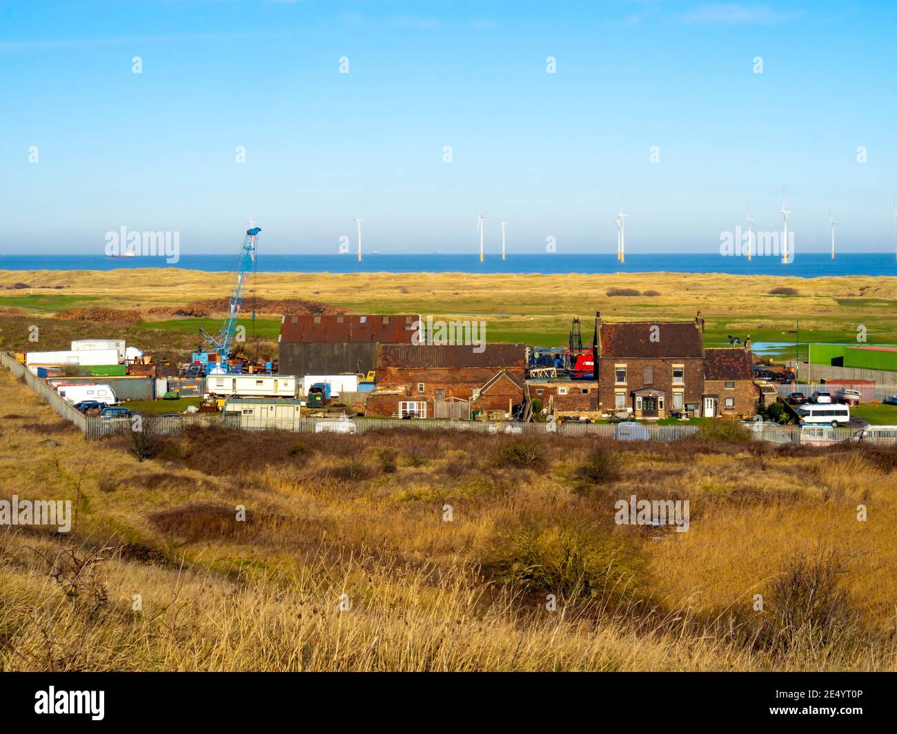 Grade 2 listed Marsh Farm House, once isolated on Warrenby marsh, now surrounded by industry and with Redcar Wind farm and the golf links behind Stock Photo