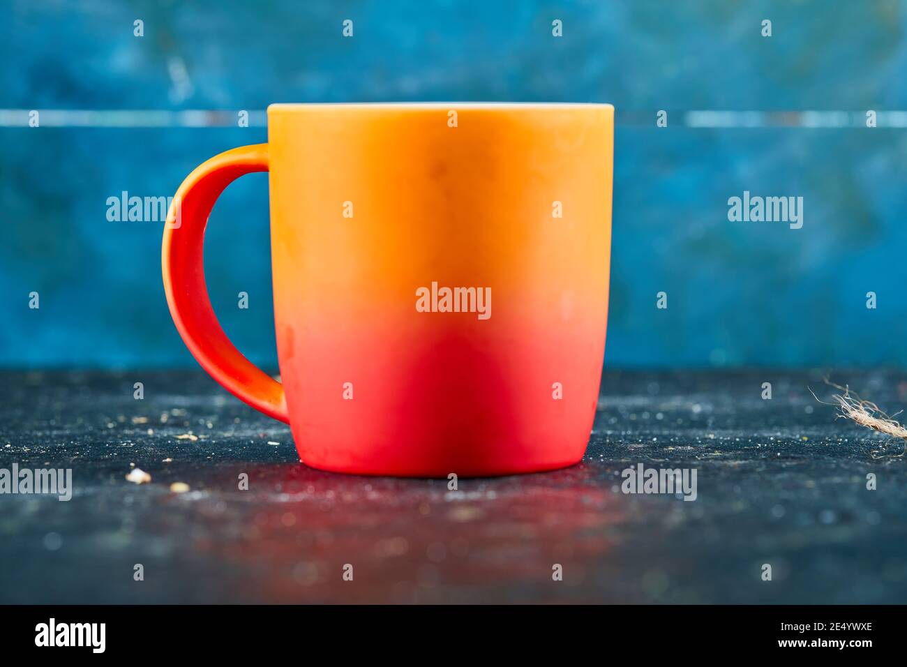 Colorful ceramic mug isolated on blue desk Stock Photo